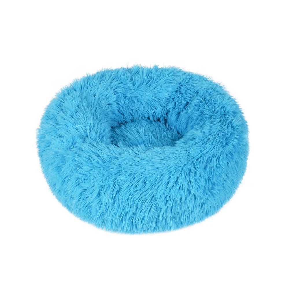 Coussin rond bleu à poils longs, avec rebord surélevé et creux central, sur fond blanc.