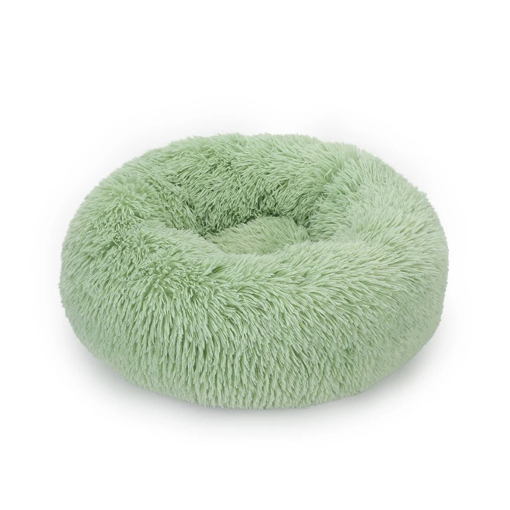 Coussin rond vert clair à poils longs, avec rebord surélevé et creux central, sur fond blanc.